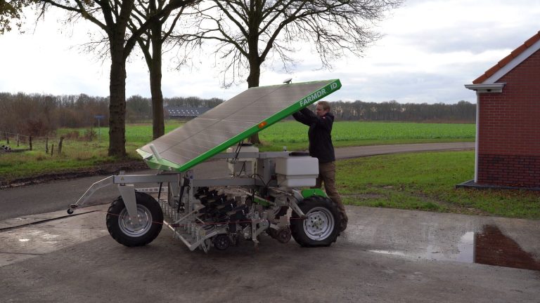 Gert Sterenborg standing by his FarmDroid robot by a chicory field, talking about his experience with precision weeding and targeted spraying to reduce chemical use.