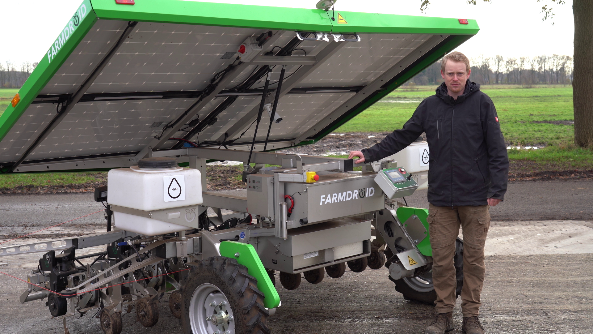 Gert Sterenborg standing by his FarmDroid robot by a chicory field, talking about his experience with precision weeding and targeted spraying to reduce chemical use.