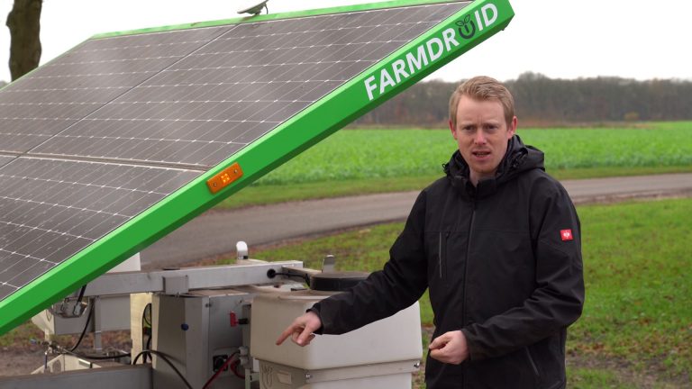 Gert Sterenborg standing by his FarmDroid robot by a chicory field, talking about his experience with precision weeding and targeted spraying to reduce chemical use.
